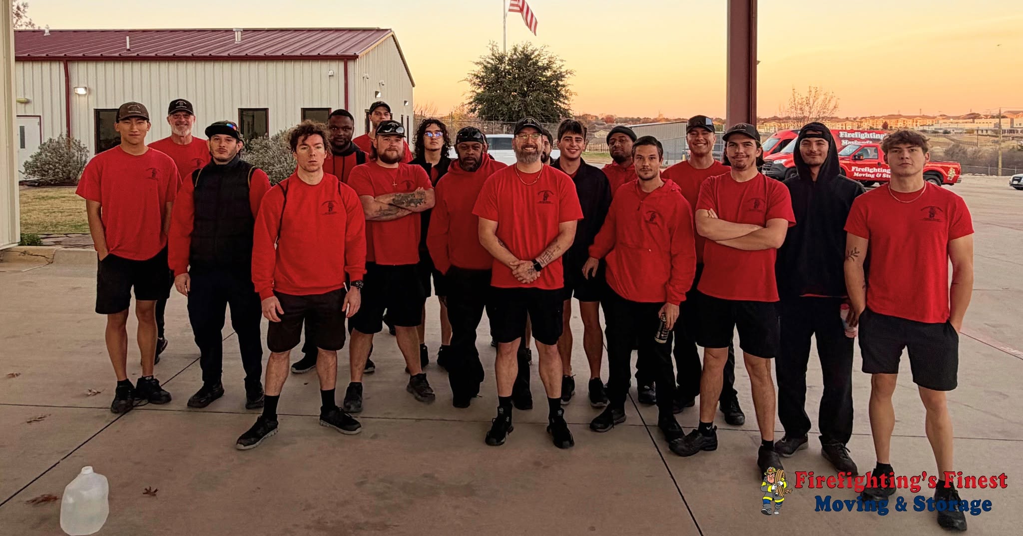 A large group of professional movers in red company shirts posing together outside their facility, representing the dedicated Firefighting's Finest Moving & Storage team ready to serve Allen, TX.